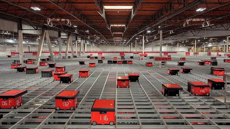 Tientallen rode AutoStore-robots op een groot magazijngrid.