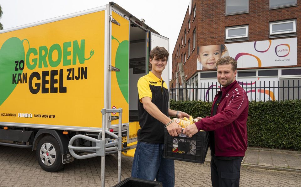 Jumbo-bezorger geeft krat boodschappen aan medewerker voor Partou-locatie.