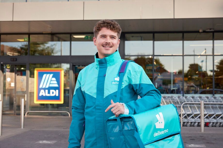 Deliveroo-bezorger met tas voor een Aldi-supermarkt.