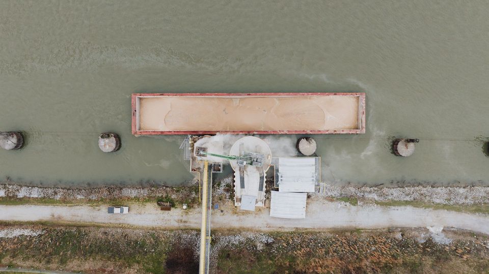 Drone-opname van binnenvaartschip met bulklading aangemeerd aan kade.