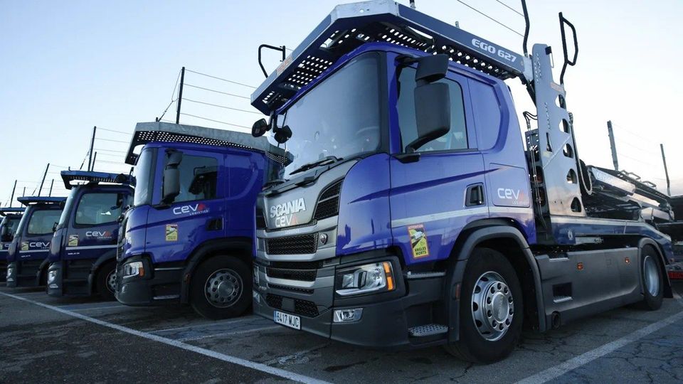 Rij blauwe Scania-autotransporters van CEVA Logistics geparkeerd op een terrein.
