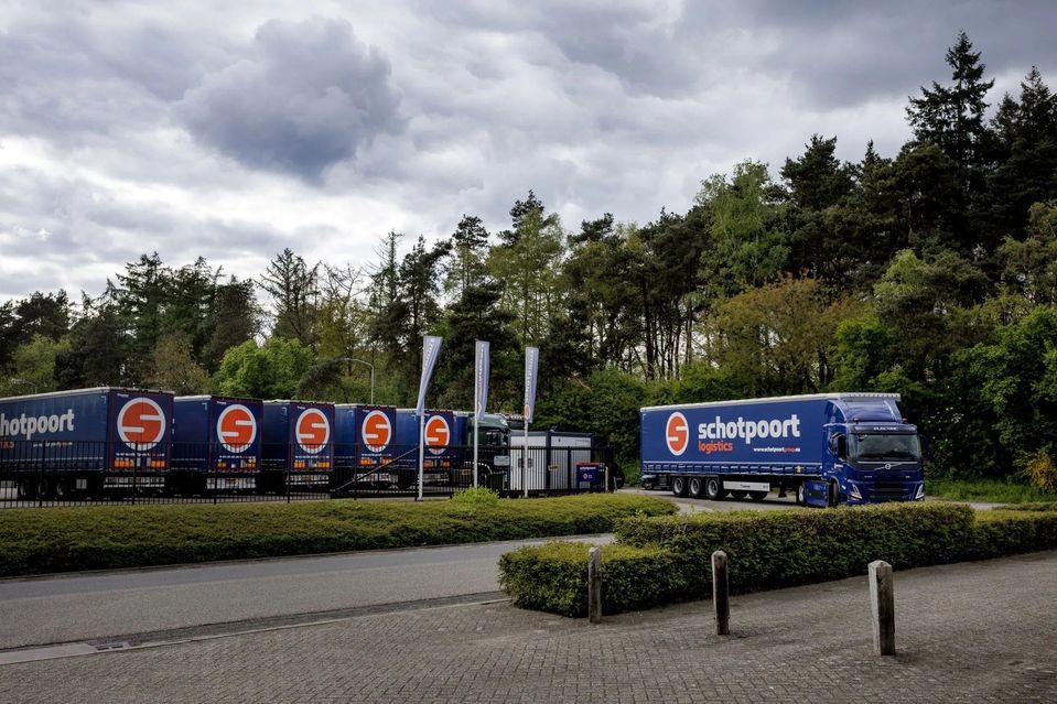 Blauwe vrachtwagens en opleggers van Schotpoort Logistics bij de inrijpoort.
