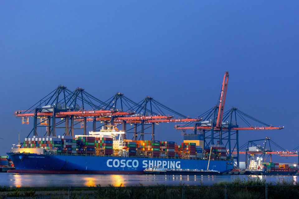 Containerschip Cosco Portugal met kraaninstallaties in haven bij avond.