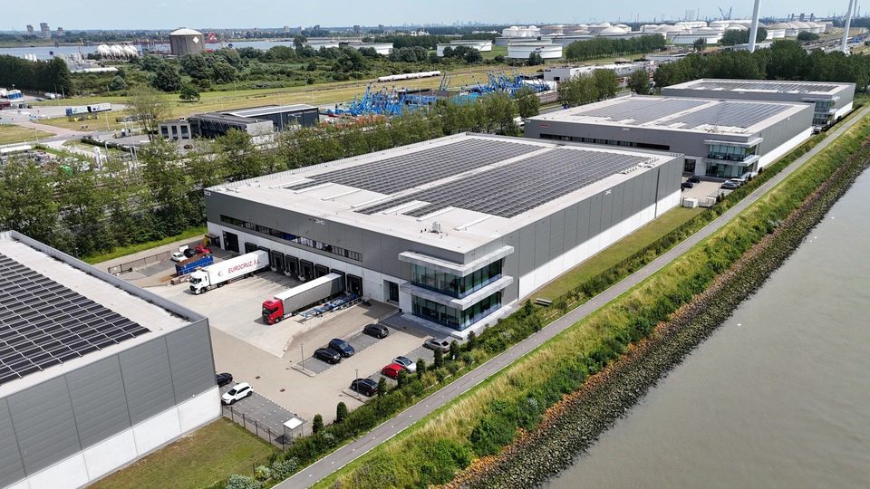 Luchtfoto van distributiecentrum met zonnepanelen aan havenwaterkant.