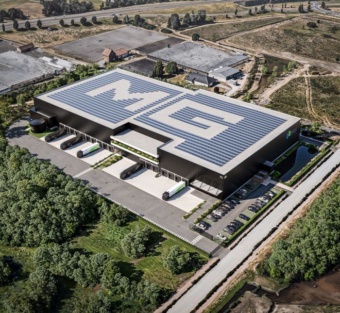 Luchtfoto-render van distributiecentrum met zonnepanelen op dak en vrachtwagens bij laaddoks.
