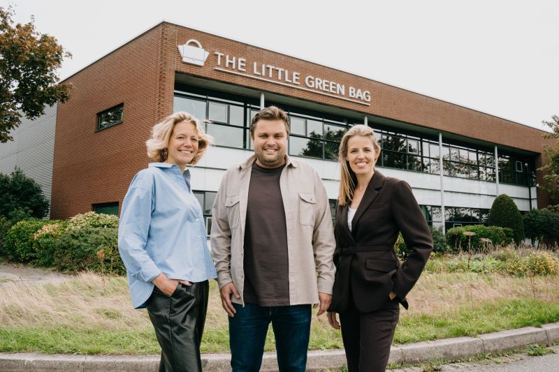 Drie mensen poseren voor het kantoorgebouw van The Little Green Bag.