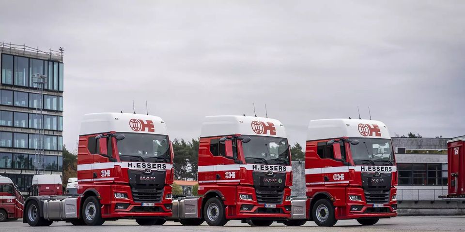 Drie rode MAN TGX-trekkers van H.Essers geparkeerd op een terrein.