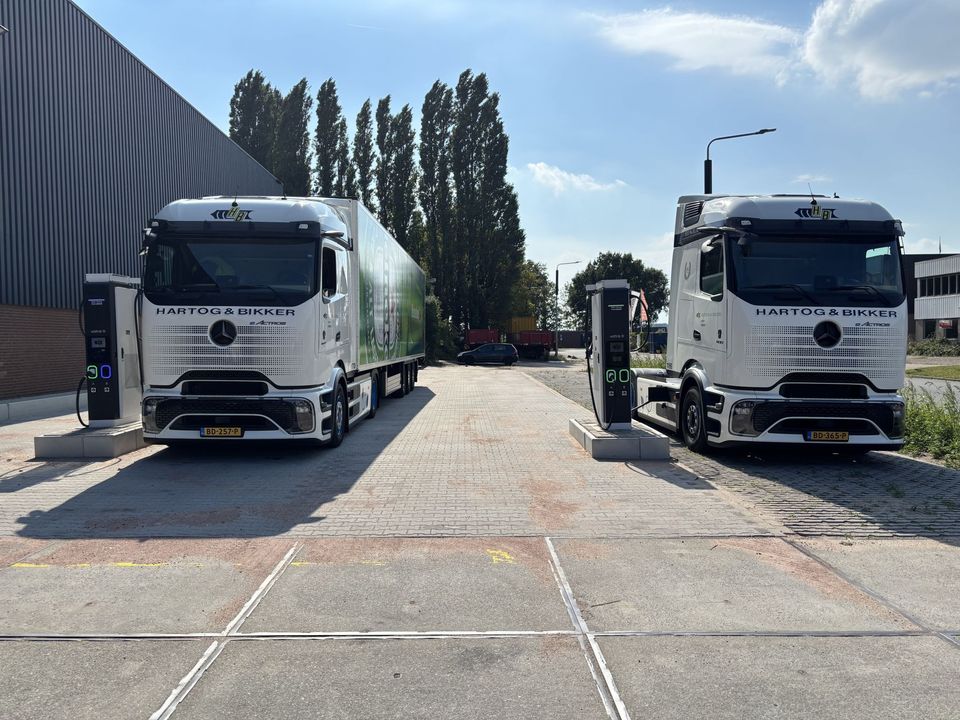 Twee elektrische Mercedes eActros trekkers van Hartog & Bikker aan laadpalen.