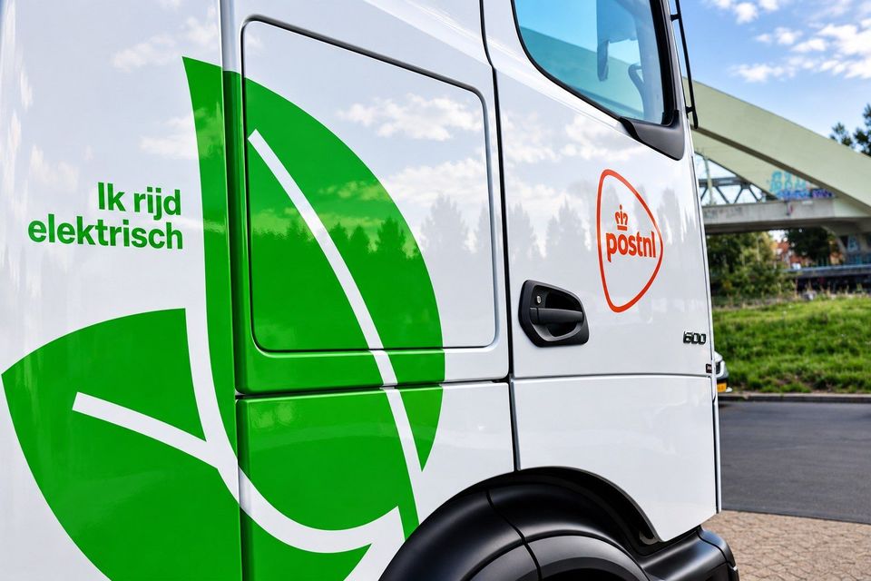 Cabine van elektrische PostNL-vrachtwagen met groen bladmotief en logo.