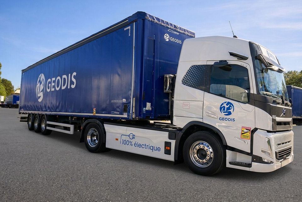 Witte elektrische vrachtwagen met blauwe GEODIS-oplegger geparkeerd op een terrein.