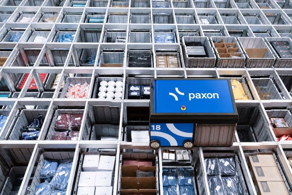 Paxon-robot rijdt door geautomatiseerd opslagsysteem met bakken vol producten.
