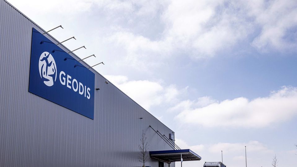 Gevel van GEODIS-distributiecentrum met groot blauw logo tegen bewolkte lucht.