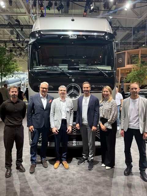 Zes personen staan voor een Mercedes-Benz Actros L truck op een beurs.