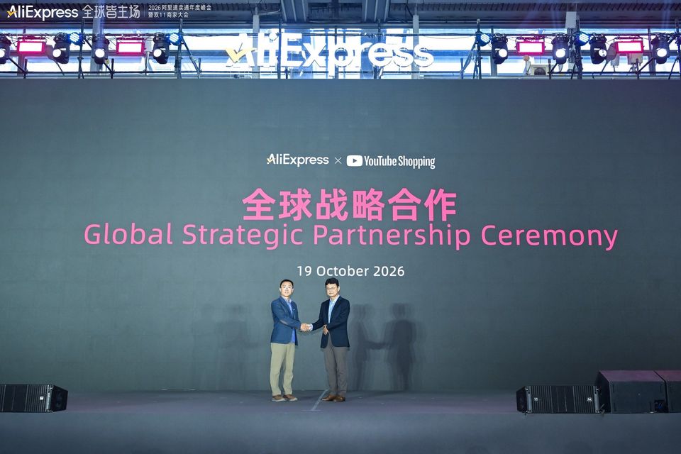 Twee mannen schudden handen op podium tijdens AliExpress YouTube-partnerschapceremonie.