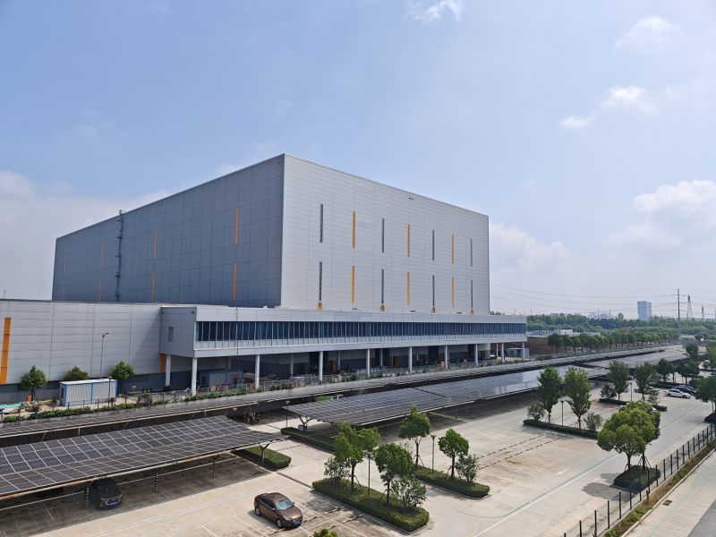 Groot grijs hoogbouwmagazijn met zonnepanelen op parkeerterrein in Hefei.