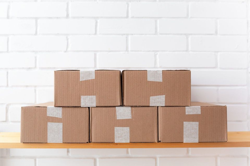Vijf kartonnen dozen met tape gestapeld op een houten plank.