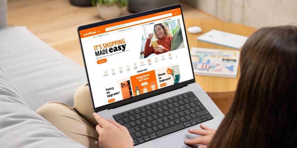 Vrouw bekijkt de oranje homepage van easyShop.com op laptop.