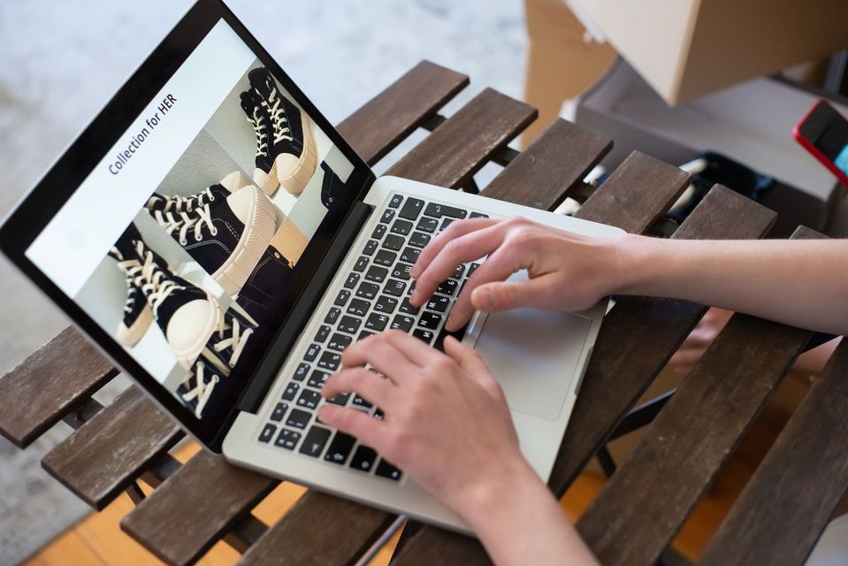 Handen op laptop met webshop van sneakers op het scherm.