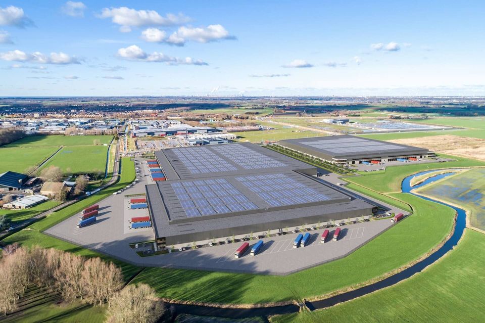 Luchtfoto van distributiecentra met zonnepanelen op dak in polderlandschap.