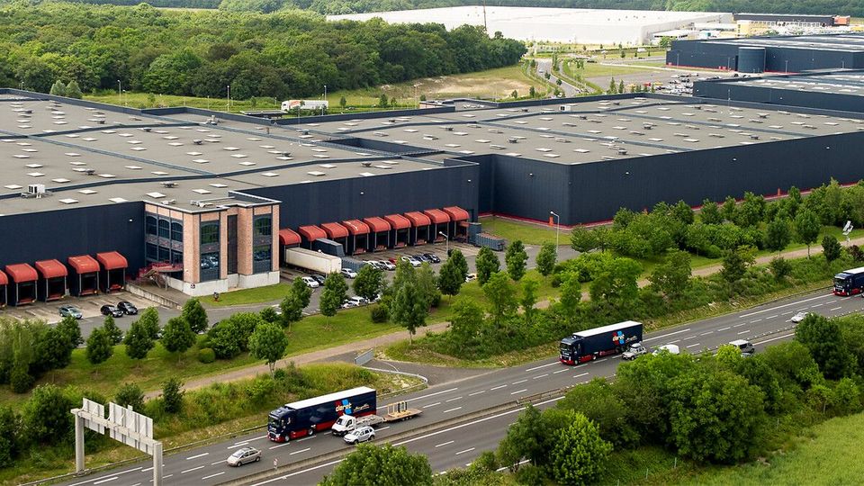Luchtfoto van groot distributiecentrum met Deret-vrachtwagens op snelweg.