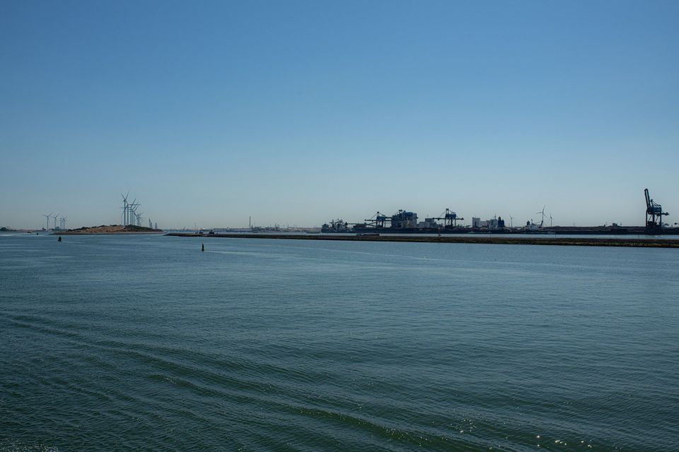 Waterweg met zicht op de Maasvlakte met windmolens en havenkranen.