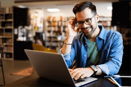 man-laptop-bibliotheek-glimlach