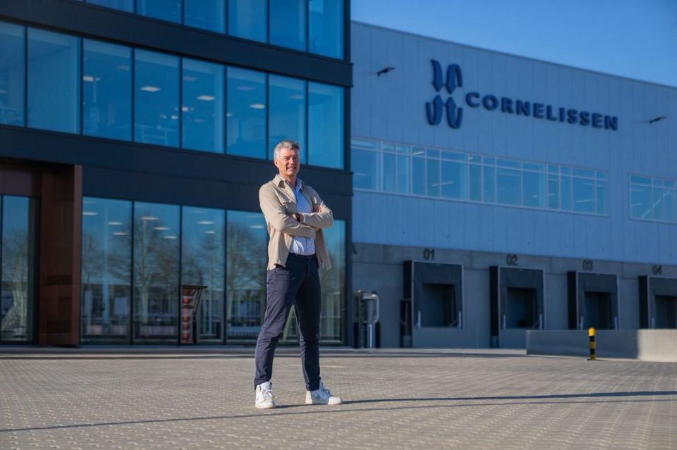 Man staat met gekruiste armen voor distributiecentrum met Cornelissen-logo.