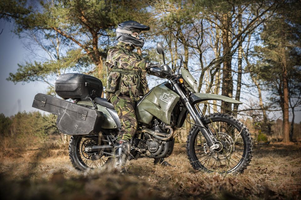 Militair in camouflage op groene KTM-motor in bos.