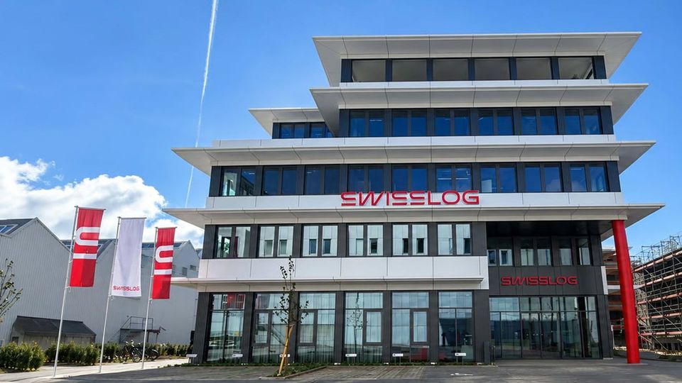 Buitenaanzicht van het nieuwe Swisslog-hoofdkantoor in Aarau met vlaggen.
