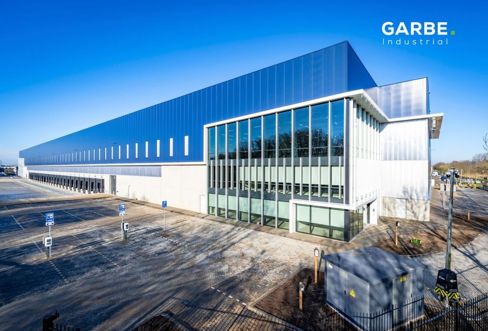 Buitenaanzicht nieuwbouw distributiecentrum met laaddocks en glazen kantoorvleugel in Veghel.