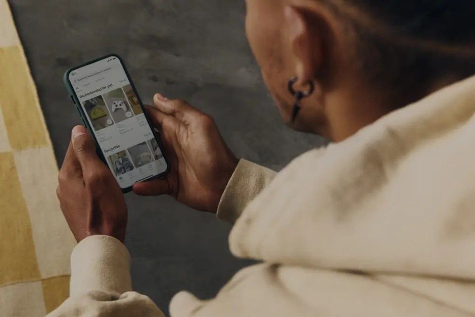 Persoon houdt smartphone vast met tweedehands marktplaats-app in beeld.