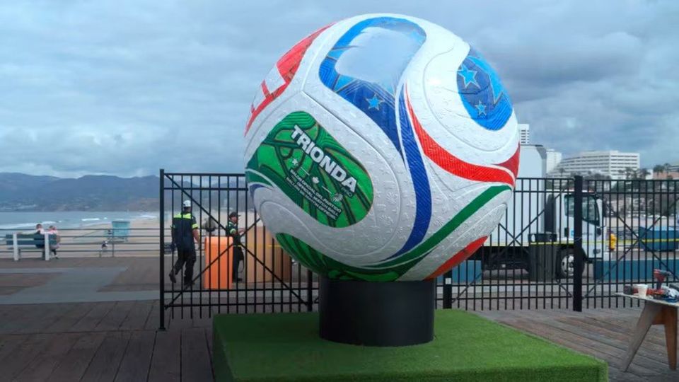 Reusachtige adidas Trionda voetbalreplica op podium aan strandboulevard.