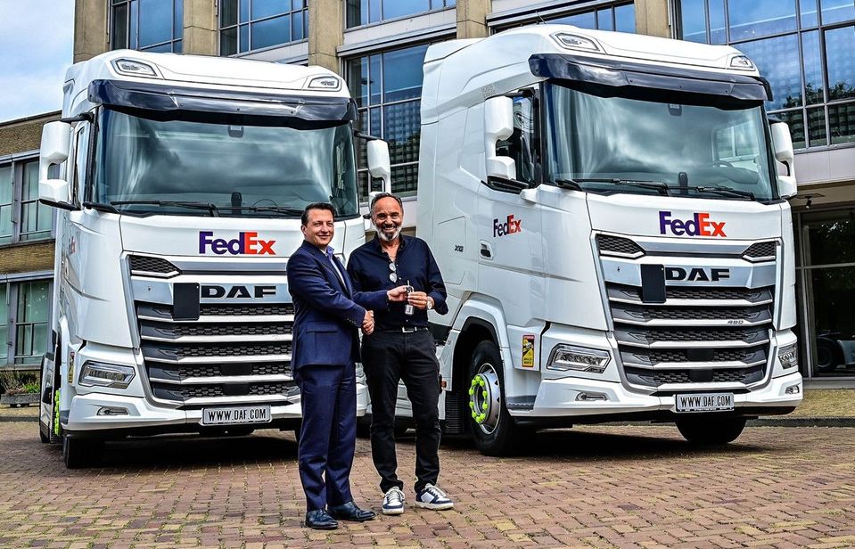 Twee mannen wisselen sleutels uit voor twee witte DAF FedEx-trekkers.