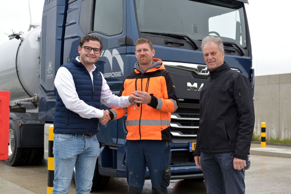 Drie mannen bij sleuteloverdracht voor blauwe MAN waterstoftrekker van Transpose.