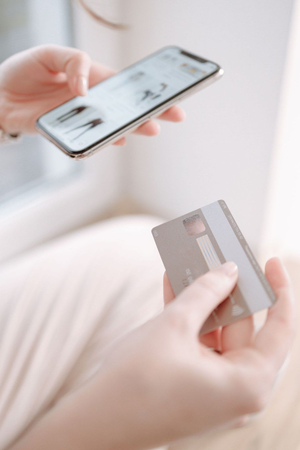 Handen houden smartphone met webshop en betaalpas vast.