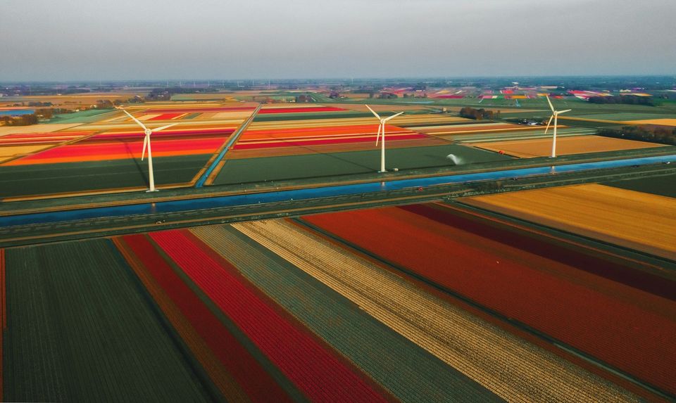 Luchtfoto van Nederlandse polder met snelweg, kanaal en windmolens.