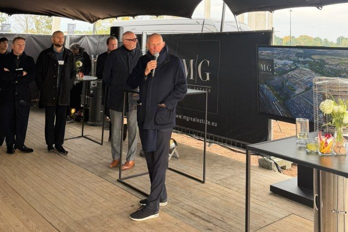 Spreker met microfoon bij ceremonie MG Real Estate.