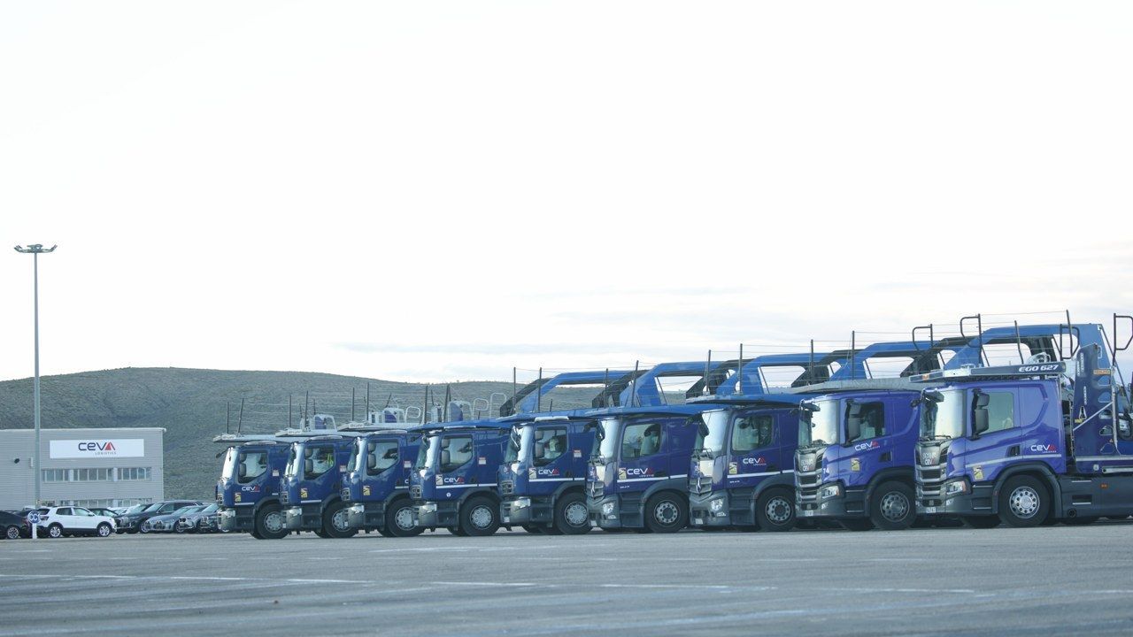 Rij blauwe CEVA Logistics autotransporters op logistiek terrein.