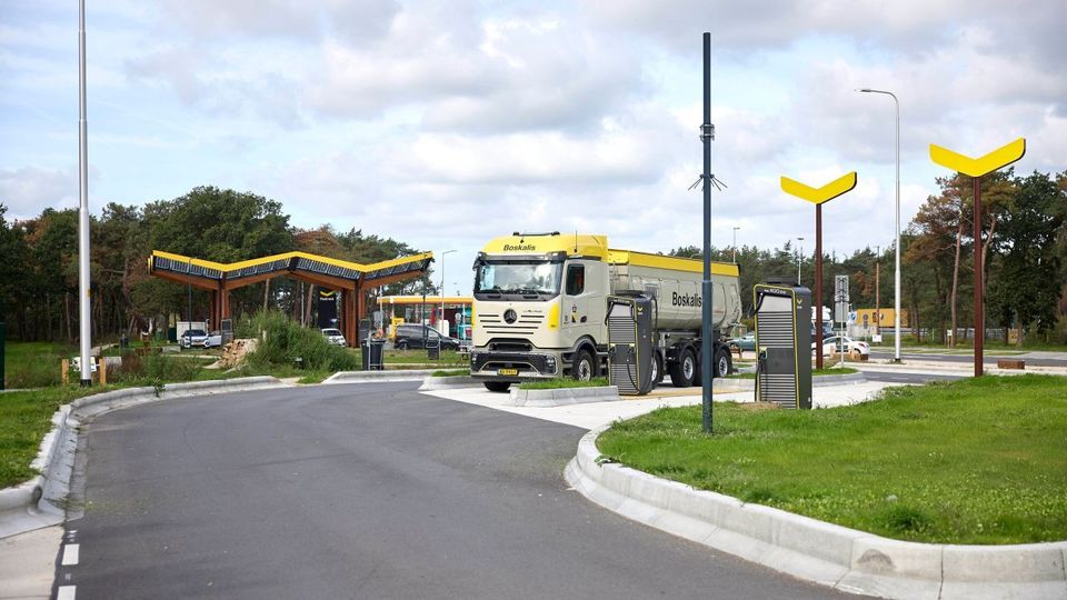 Elektrische vrachtwagen bij Fastned laadstation langs de snelweg.